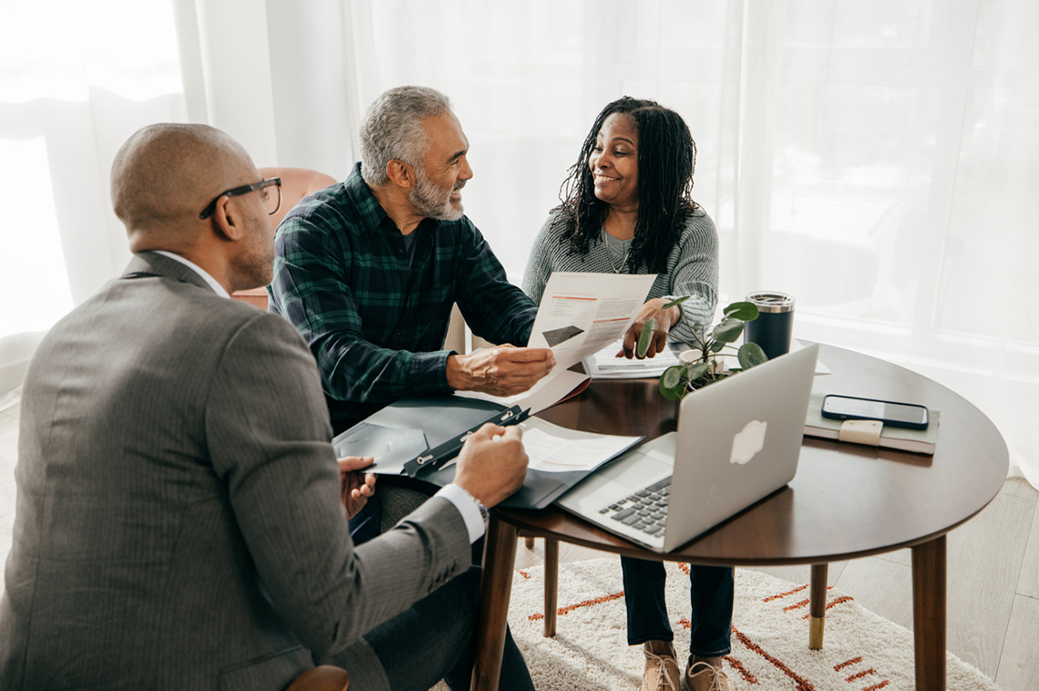 Realtor with his clients, sitting at a table together providing ultimate service