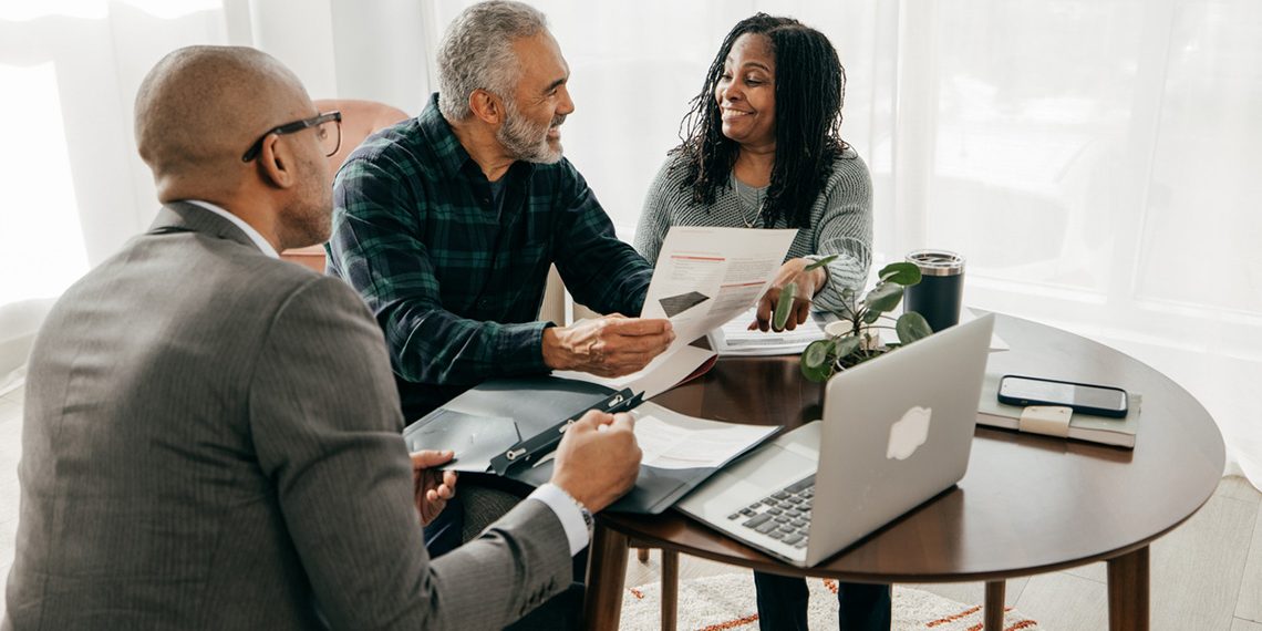 Realtor with his clients, sitting at a table together providing ultimate service